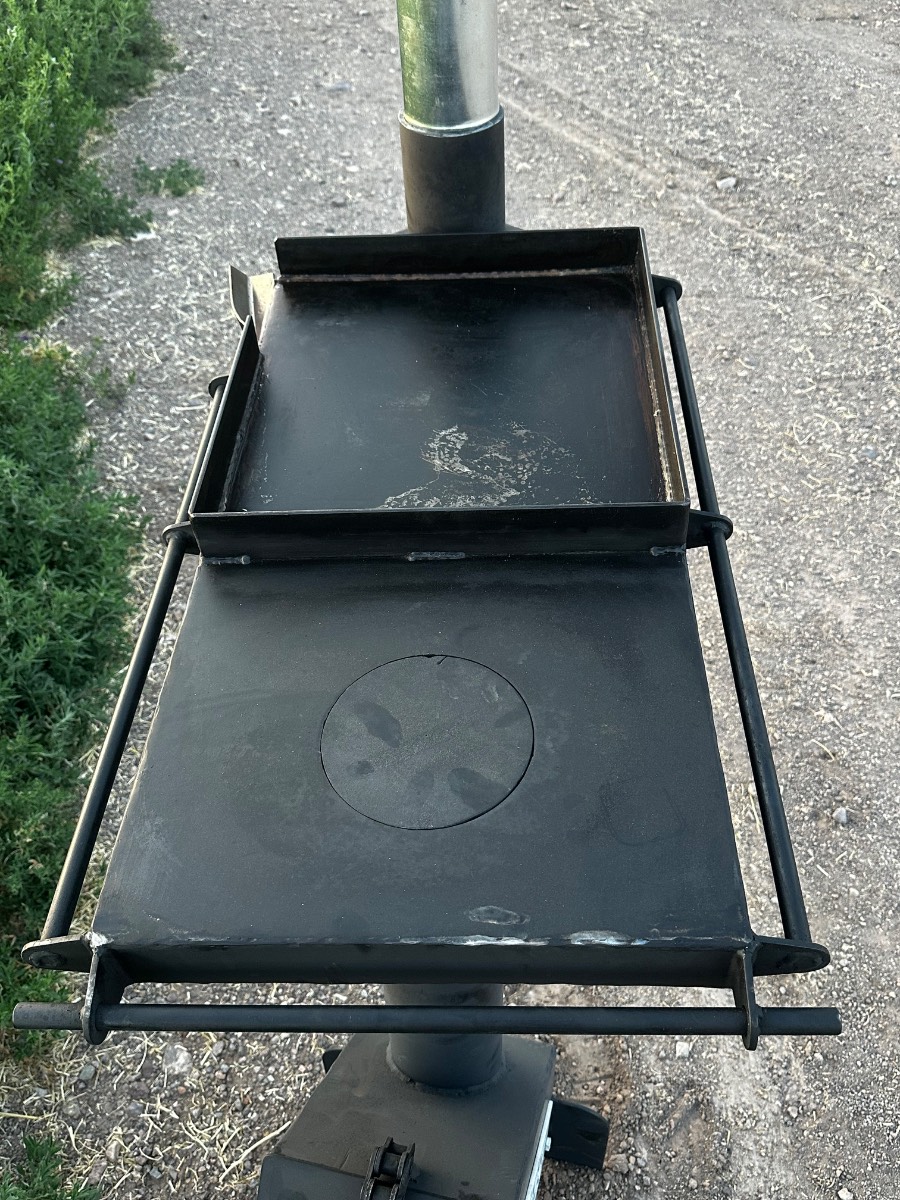 Iron Rocket Stove burning wood below a flat cooking top